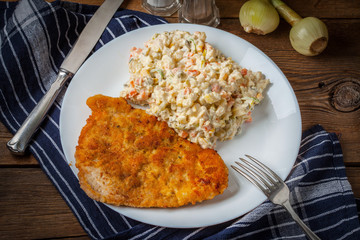 Fried pork chop in breadcrumbs, served with vegetable salad.