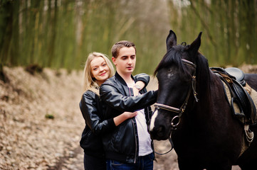 Obraz premium Young stylish couple in love near horse at autumn forest.
