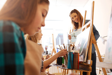 Smiling young teacher using modern gadget in the studio