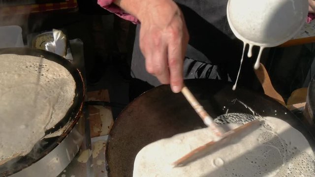 4K close up of a man spreading crepe batter a crepe, or buckwheat pancake, in his cr&ecirc;perie restaurant, in Brittany. French traditional food.  Galette bretonne, creperie, Rennes, Bretagne, France.