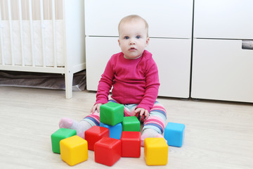 Lovely 10 months baby girl playing blocks at home