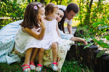 Fototapeta premium Parents and their little children sit on wooden bridge in the forest