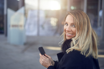 Lächelnde blonde Geschäftsfrau mit ihrem Handy