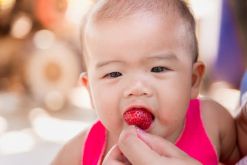 Asian baby girl eating strawberries.