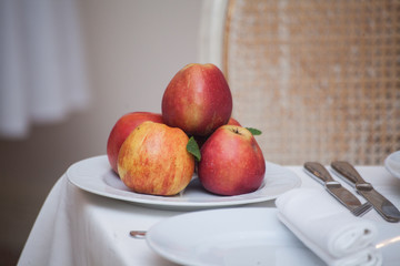 Red apples in a plate on white table,