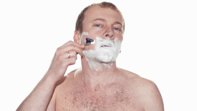 Adult man shaving with foam and manual razer. Slow motion