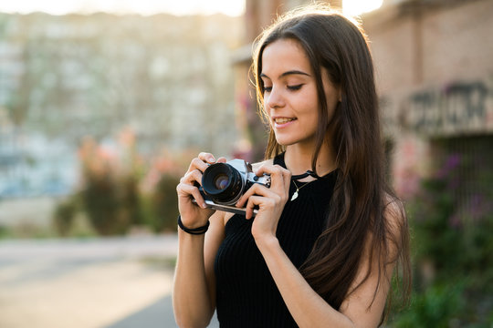 Smiling young woman adjusting camera
