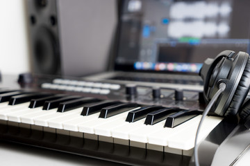 Synthesizer keyboard and headphone lying on Music studio working desktop