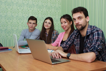 Fototapeta premium Happy friends using laptop while sitting at library table. Group study university library