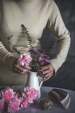 Midsection of woman arranging flowers in vase