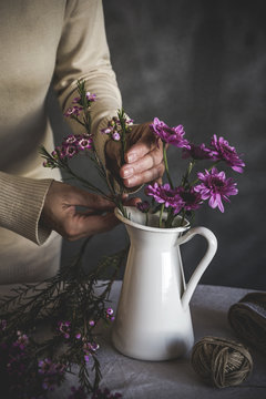 Midsection of woman arranging flowers in vase