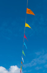 Colorful flags hanging on wire against blue sky