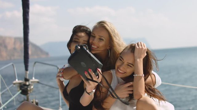 Girls taking selfies on yacht. Young models on vacation