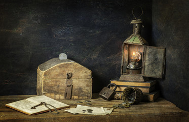 Fototapeta na wymiar Classic still life with old savings box placed with vintage lamp,old books.coins, key and lock on rustic wooden background..