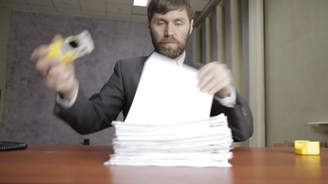 Businessman nervously signing and stamping incoming documents. office worker scatter documents around