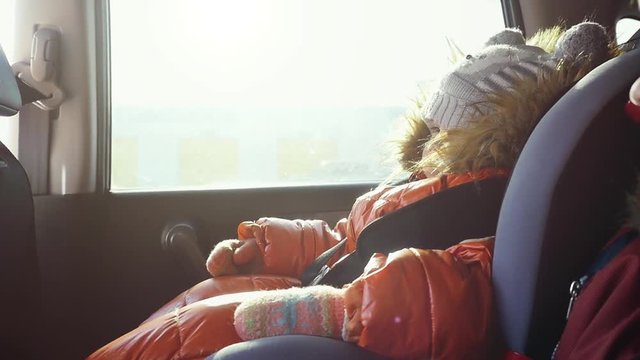 Dreaming cute child in a car in the child safety seat in slow motion on sunny day. 1920x080