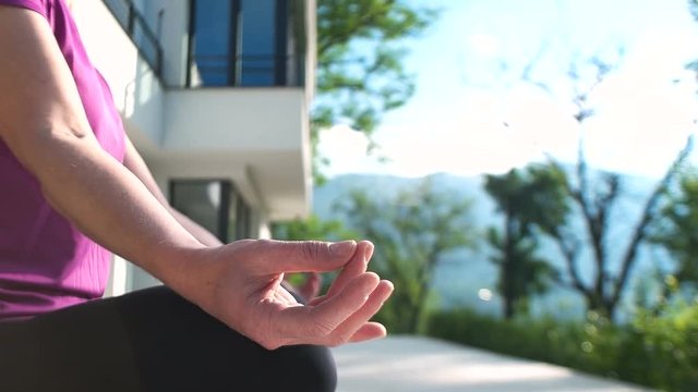 Woman practicing Yoga in front of luxary mansion