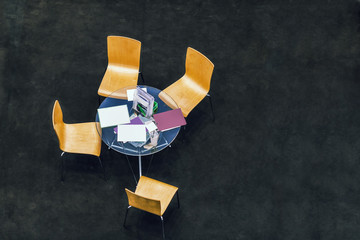 Top view of a small business meeting round table with four chairs on black floor copy space