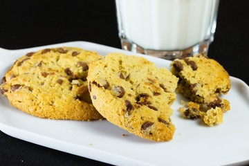 Chocolate chip cookies with milk on black background