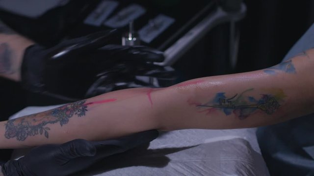 tattoo artist prepares the client's arm before applying the tattoo in slow motion.