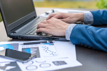 Handsome businessman wearing suit and using modern laptop outdoors and graph finance diagram.