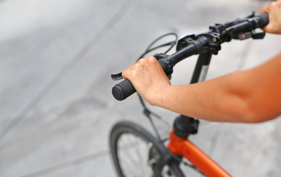 Woman riding a bicycle. Closeup on handlebar with female hand. Healthy lifestyle and sport concept