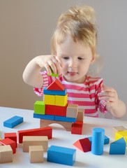 Little baby girl playing with wooden colorful cubes