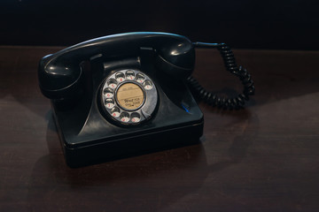Antique old black rotary telephone on the wooden table