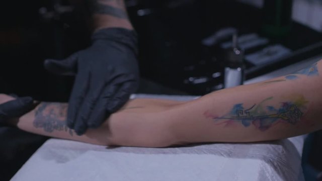 Close up shot of tattoo artist preparing skin of his client to the process of making tattoo in slow motion.