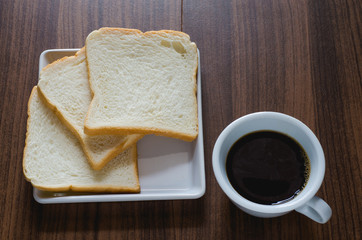 black coffee and bread on wood board.