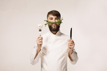 Chef's menu logo. Vegan restaurant logo. Symbol of healthy food. CONCEPT OF HEALTHY FOOD. Handsome funny cheff holding spoon and knife and herbs like a mustache. Professional chef.
