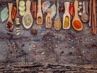 Various of spices and herbs in wooden spoons. Flat lay of spices ingredients chilli ,pepper corn, garlic, thyme, oregano, cinnamon, star anise, nutmeg, mace, ginger and bay leaves on shabby wooden.