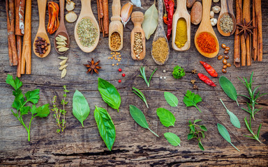 Various of spices and herbs in wooden spoons. Flat lay of spices ingredients chilli ,pepper corn, garlic, thyme, oregano, cinnamon, star anise, nutmeg, mace, ginger and bay leaves on shabby wooden.