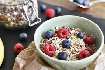 Delicious cereal breakfast with bowl and fresh fruits. Fresh blueberry and raspberry fruits, healthy eating scene.