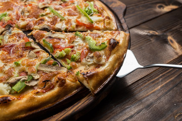 Delicious pizza with mushrooms - thin pastry crust isolated at wooden background on wooden desk