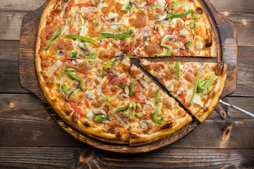 Delicious pizza with mushrooms - thin pastry crust isolated at wooden background on wooden desk