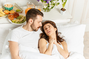 Young adult heterosexual couple lying on bed in bedroom