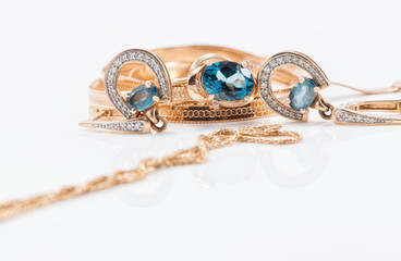 Gold earrings in the shape of a horseshoe and a delicate ring with large Topaz