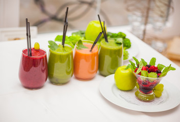 Red and green healthy smoothies with fresh ingredients on table.