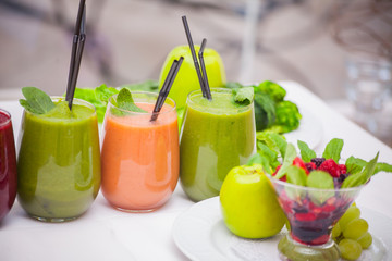 Red and green healthy smoothies with fresh ingredients on table.