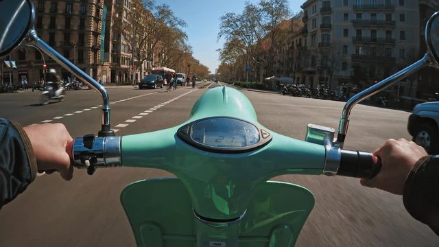 Riding battery powered electric scooter in urban traffic during commute at sunny autumn day in town, pov view