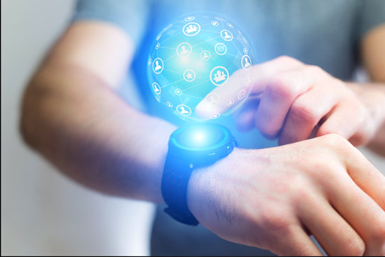 Businessman holding smartwatch with network globe sphere hologram going out - Technology concept