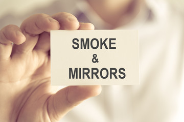 Businessman holding SMOKE AND MIRRORS message card