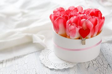 Bouquet of pink tulips in a box on a textured white background. Selective focus.