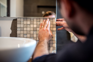 Industrial worker applying mosaic tiles in bathroom walls