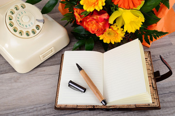 Notizbuch mit Telefon und Blumenstrauß