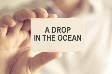 Businessman holding A DROP IN THE OCEAN message card
