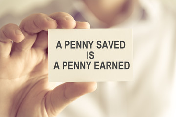 Businessman holding A PENNY SAVED IS A PENNY EARNED message card