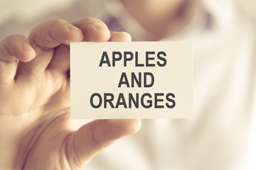 Businessman holding APPLES AND ORANGES message card