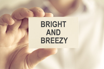 Businessman holding BRIGHT AND BREEZY message card